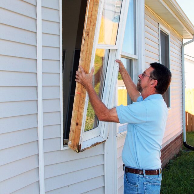 a man installing a window on a house