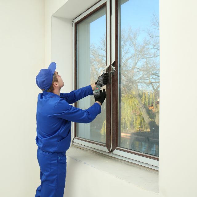 a man in blue uniform using a tool to open a window